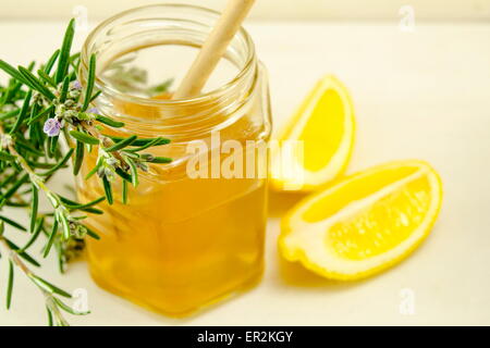 Glas Honig einen Holzlöffel und Zitronen auf einem Tisch Stockfoto