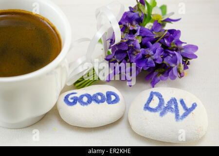 Weiße Tasse Kaffee mit Blumen und Felsen sagen: "Guten Tag" Stockfoto