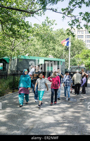 New York City Montag, 25. Mai 2015, USA; Amerikanische Flagge weht auf Halbmast in DeWitt Clinton Park wie entspannte multiethnischen Amerikaner unter alten schattenspendenden Bäumen Credit spazieren: Dorothy Alexander/Alamy Live News Stockfoto