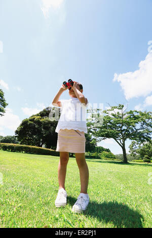 Junge Japanerin mit dem Fernglas in einem Stadtpark Stockfoto