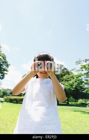 Junge Japanerin mit dem Fernglas in einem Stadtpark Stockfoto