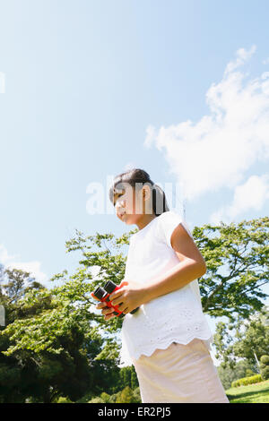 Junge Japanerin mit dem Fernglas in einem Stadtpark Stockfoto