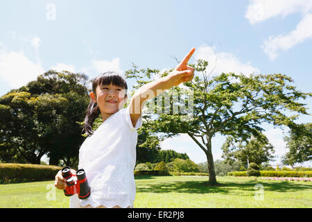 Junge Japanerin mit dem Fernglas in einem Stadtpark Stockfoto