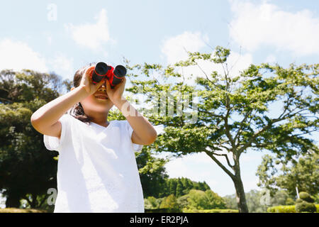 Junge Japanerin mit dem Fernglas in einem Stadtpark Stockfoto