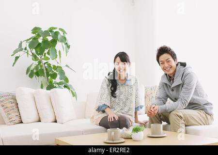 Junge Erwachsene paar entspannen auf dem Sofa und lächelt in die Kamera Stockfoto