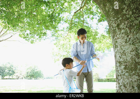 Glückliche japanischen Vater und Sohn fangen Insekten in einem Stadtpark Stockfoto