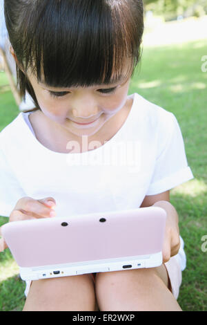 Japanische Mädchen spielen von Videospielen in einem Stadtpark Stockfoto