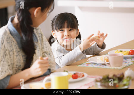 Junge Erwachsene Mutter und Tochter lächelnd an einander beim Frühstück Stockfoto