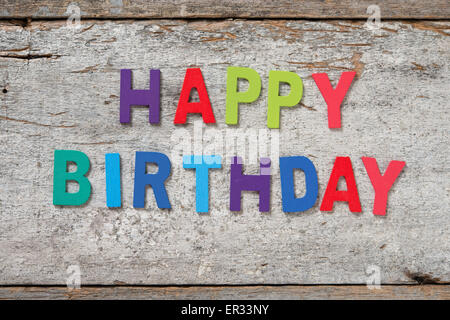 Die bunten Worte 'HAPPY BIRTHDAY' mit Holzbuchstaben auf alten Holzbrett gemacht. Stockfoto
