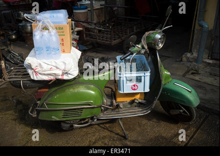 BANGKOK, THAILAND - 27. Oktober 2014: Ein traditionelle alte grüne Roller beladen mit Taschen steht auf einer dunklen Gasse geparkt. Stockfoto