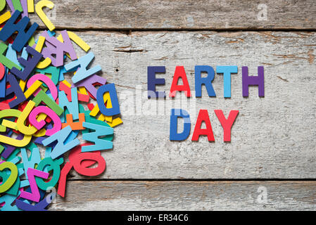 Die bunten Worte "EARTH DAY" alten Holzbrett mit Holzbuchstaben neben einem Haufen von anderen Buchstaben gemacht. Stockfoto