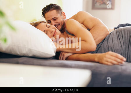Junges Paar auf Bett liegend zusammen im Schlafzimmer verliebt. Glücklicher Mann und Frau morgens aufwachen. Stockfoto