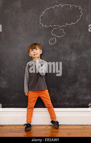 Kind mit einer Sprechblase auf der Tafel zu denken. Voller Länge Schuss von niedlichen kleinen Jungen zu Hause stehen. Inspiration und so Stockfoto