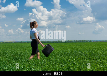 Mädchen mit einer Aktentasche zu Fuß auf dem Rasen Stockfoto