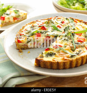Eine hausgemachte Quiche mit Gemüse wie Brokkoli und Tomaten und Kräutern. Stockfoto