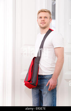 Eine junge blonde Mann kommenden Heim vorbei durch die Tür. Stockfoto