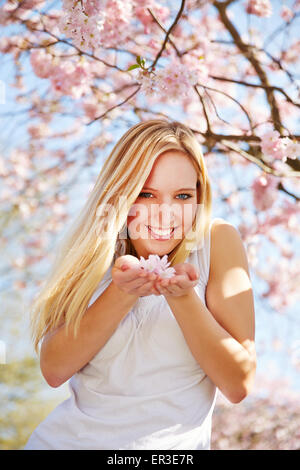 Junge Frau riechen Kirschblüten in einem Park im Frühjahr Stockfoto