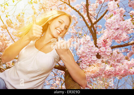 Junge glücklich Frau hält stören ihre Daumen oben am Kirschbaum Blüte Stockfoto