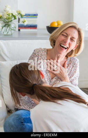 Zwei Frauen lachen; Blick über die Schulter hinter einer Frau. Stockfoto