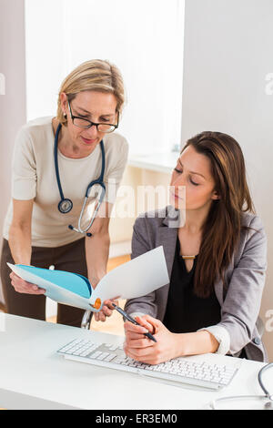 Arzthelferin erhält Anweisungen des Arztes, die sie unterstützt. Stockfoto