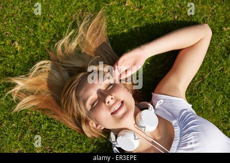 Junge blonde Frau, die im Sommer im grünen Rasen in einem Park zu legen Stockfoto