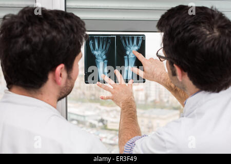 Rheumatologe (rechts) und interne Untersuchung Röntgenaufnahmen der Hände eines Patienten mit rheumatoider Arthritis, Krankenhaus in Bordeaux, Frankreich. Stockfoto
