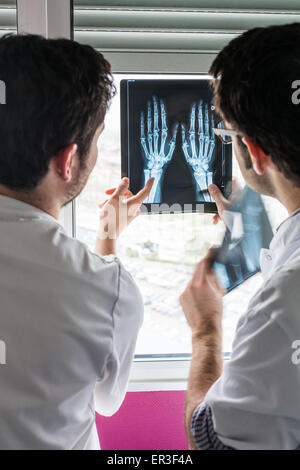 Rheumatologe (rechts) und interne Untersuchung Röntgenaufnahmen der Hände eines Patienten mit rheumatoider Arthritis, Krankenhaus in Bordeaux, Frankreich. Stockfoto