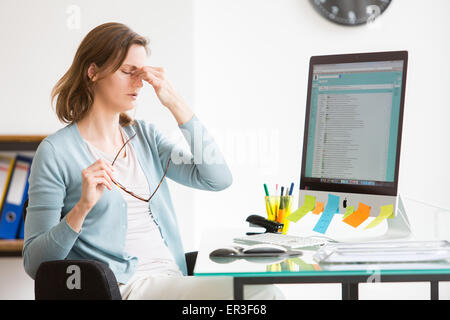 Frau bei der Arbeit, die unter Kopfschmerzen leiden. Stockfoto