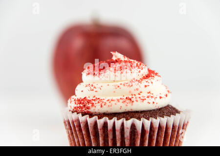 roter Apfel Vs red Velvet Cupcake - Snack Entscheidung zwischen gesunde Ernährung oder Junk-food Stockfoto