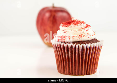 roter Apfel Vs red Velvet Cupcake - Snack Entscheidung zwischen gesunde Ernährung oder Junk-food Stockfoto