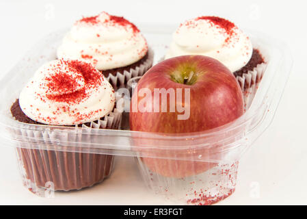 roter Apfel Vs red Velvet Cupcake - Snack Entscheidung zwischen gesunde Ernährung oder Junk-food Stockfoto