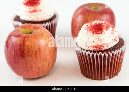 roter Apfel Vs red Velvet Cupcake - Snack Entscheidung zwischen gesunde Ernährung oder Junk-food Stockfoto