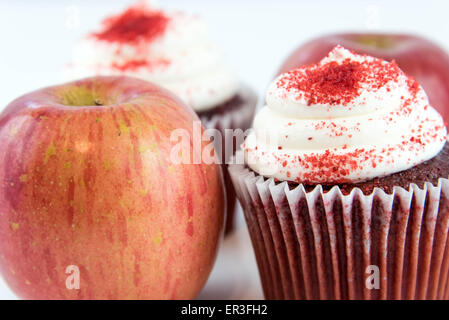 roter Apfel Vs red Velvet Cupcake - Snack Entscheidung zwischen gesunde Ernährung oder Junk-food Stockfoto