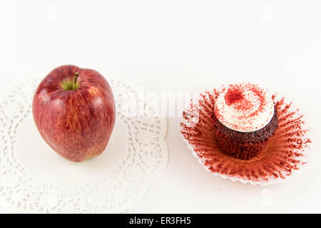 roter Apfel Vs red Velvet Cupcake - Snack Entscheidung zwischen gesunde Ernährung oder Junk-food Stockfoto