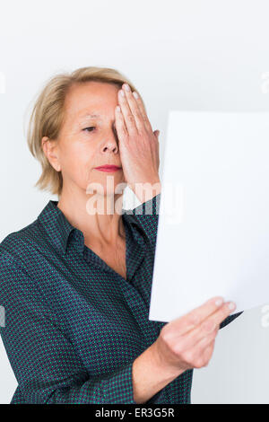 Ältere Frau betrachten ein Amsler-Gitters, Makula-Degeneration zu erkennen. Stockfoto