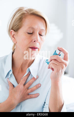 Frau mit einem Aerosol-Inhalator, der Bronchodilatator zur Behandlung von Asthma, den Inhalator enthält weitet Lunge Atemwege um die Atmung zu verbessern. Stockfoto