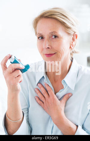 Frau mit einem Aerosol-Inhalator, der Bronchodilatator zur Behandlung von Asthma, den Inhalator enthält weitet Lunge Atemwege um die Atmung zu verbessern. Stockfoto