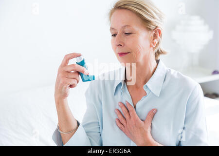 Frau mit einem Aerosol-Inhalator, der Bronchodilatator zur Behandlung von Asthma, den Inhalator enthält weitet Lunge Atemwege um die Atmung zu verbessern. Stockfoto