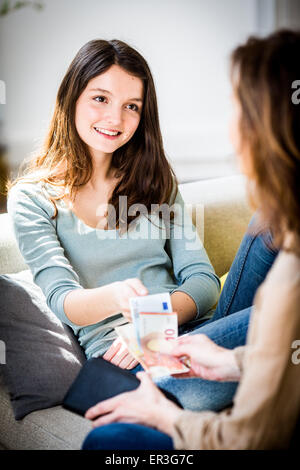 Mutter gibt ihrer Tochter Taschengeld. Stockfoto