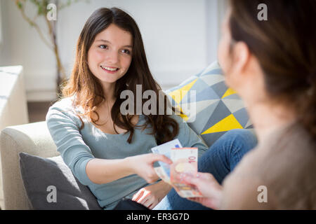 Mutter gibt ihrer Tochter Taschengeld. Stockfoto