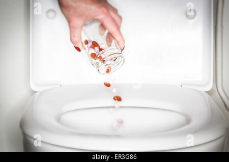 Hand, die Pillen in einer Toilette zu werfen. Stockfoto
