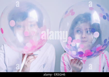 Kinder versteckt sich hinter transparenten Luftballons Stockfoto