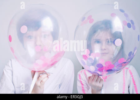 Kinder versteckt sich hinter transparenten Luftballons Stockfoto