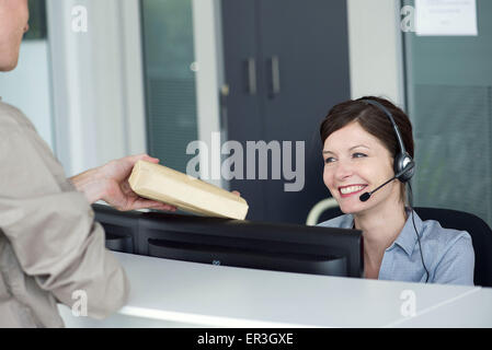 Angestellte an der Rezeption empfangen Paket vom Zusteller Stockfoto