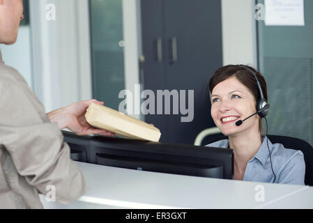 Angestellte an der Rezeption empfangen Paket vom Zusteller Stockfoto