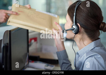 Angestellte an der Rezeption empfangen von Mails vom Zusteller Stockfoto