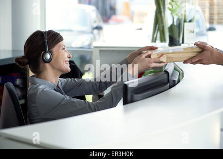 Angestellte an der Rezeption akzeptieren Paket vom Zusteller Stockfoto