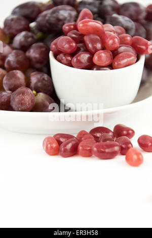 lila Trauben Vs lila Gummibärchen - Entscheidung zwischen gesunde Ernährung oder Junk-Food snack Stockfoto