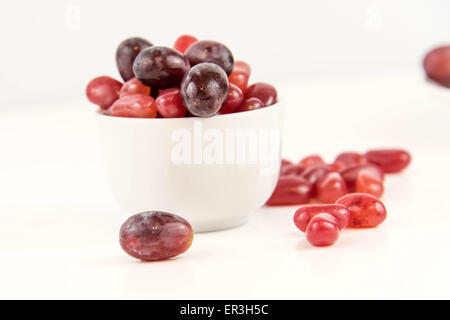 lila Trauben Vs lila Gummibärchen - Entscheidung zwischen gesunde Ernährung oder Junk-Food snack Stockfoto