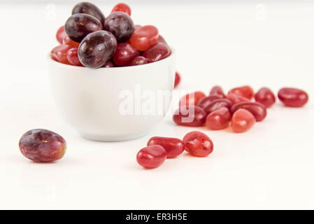 lila Trauben Vs lila Gummibärchen - Entscheidung zwischen gesunde Ernährung oder Junk-Food snack Stockfoto